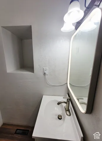 White single vanity with an integrated sink, brushed nickel faucet, and wood-finish flooring
