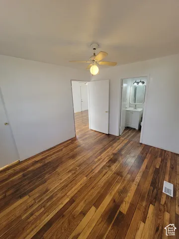 Hardwood flooring, ceiling fan with integrated lighting, white interior doors, and a bathroom with a vanity sink and mirrored medicine cabinet
