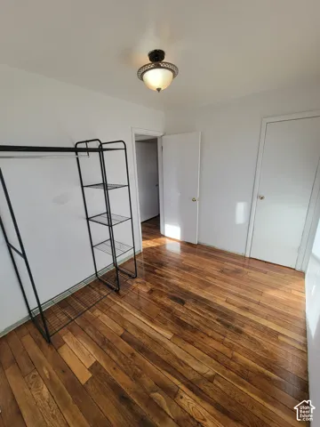 Rich wood-finish flooring, bright white walls, and a ceiling-mounted light fixture