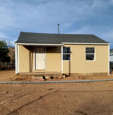Single-story structure featuring a neutral-toned exterior, dark shingle roof, white trim, and a covered entry