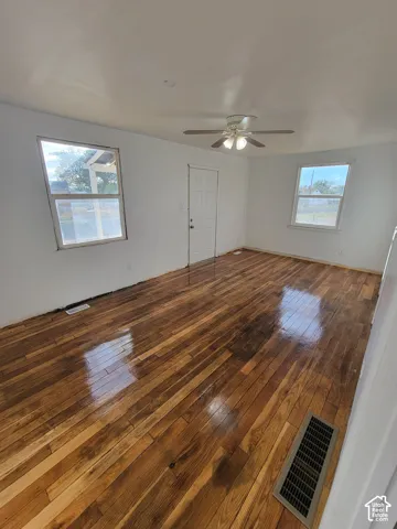 Wood-finish flooring throughout, bright white walls, and a ceiling fan with integrated lighting