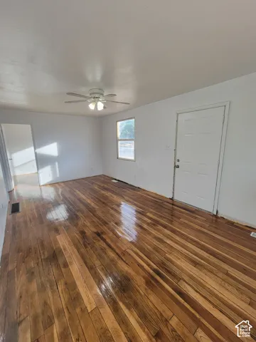 Wood-finish flooring throughout, bright white walls, and a ceiling fan with integrated lighting