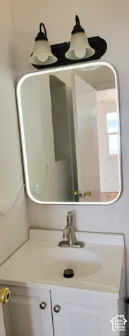 White vanity with a single basin sink, brushed nickel faucet, and white cabinetry