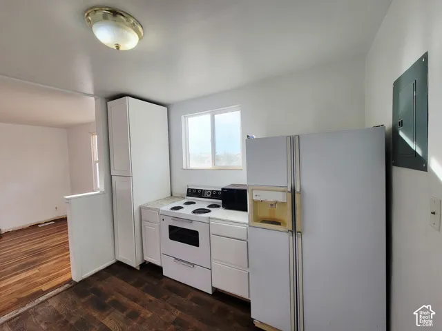 Full kitchen featuring wood-finish flooring, white cabinetry, a built-in electric range, and a window for natural light