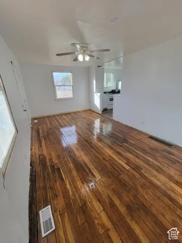 Hardwood flooring, white walls, and a ceiling fan with integrated lighting