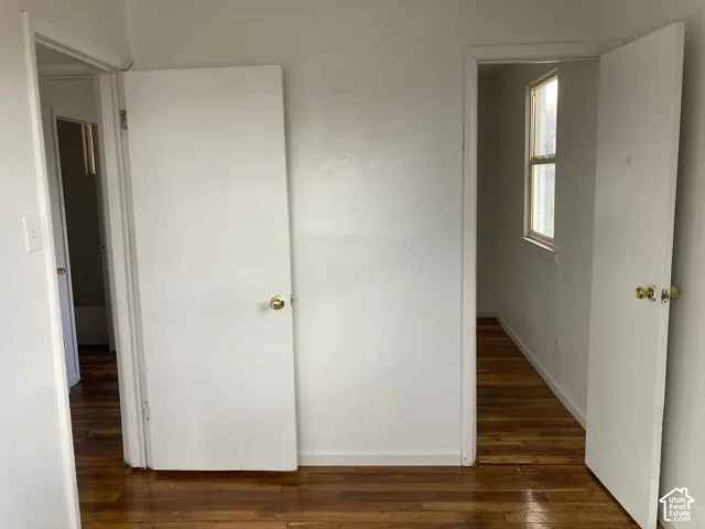 Wood-finish flooring, white painted walls, and white interior doors