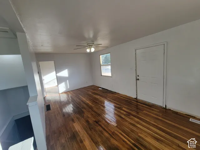 Wood-finish flooring, white walls, ceiling fan, and recessed window