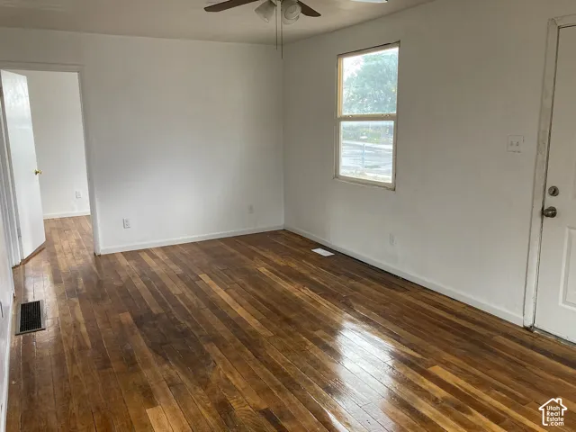 Hardwood flooring, white walls, ceiling fan, white paneled door, and a window