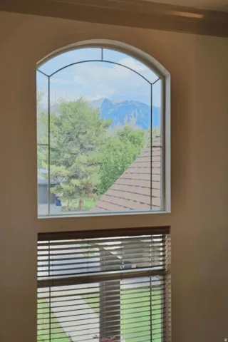 Arched window with decorative mullions, wood-finish blinds, and surrounding wall space