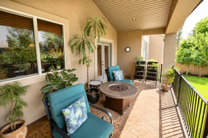 Covered outdoor patio featuring recessed lighting, a built-in fire pit, and a black wrought iron railing