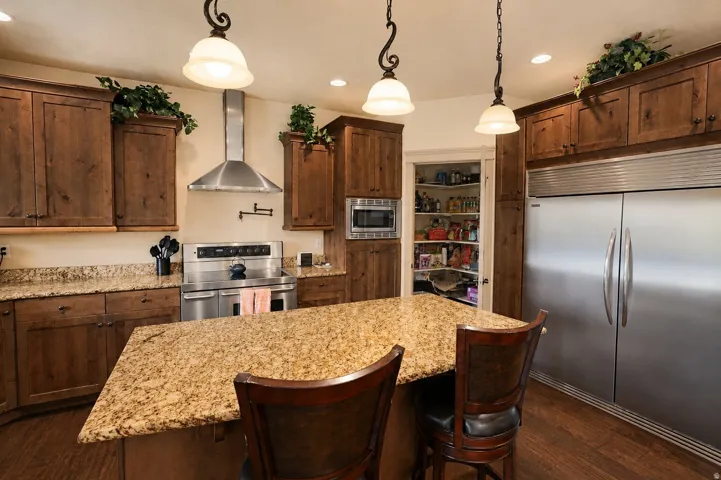 Kitchen featuring wood-finish cabinetry, granite countertops, stainless steel appliances, and a built-in pantry