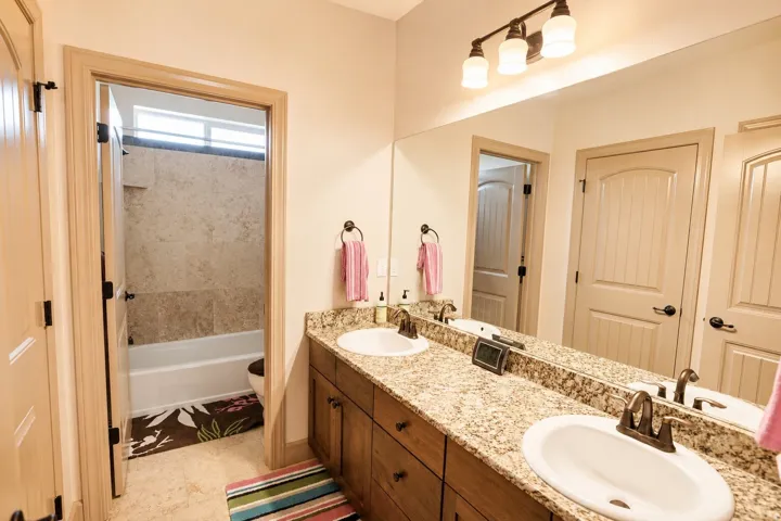 Dual sink vanity with granite countertop, wood-finish cabinetry, and oil-rubbed bronze fixtures