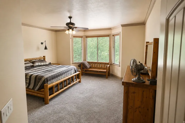 Recessed bay windows, ceiling fan with integrated lighting, wall-mounted light fixture, and crown molding