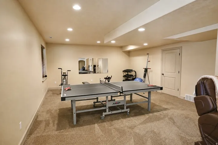 Recessed lighting, warm neutral wall paint, carpeted flooring, and a paneled interior door
