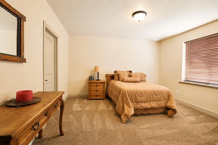 Neutral wall paint, textured ceiling, window with blinds, overhead flush mount light, and a paneled interior door