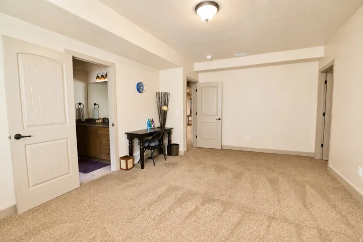 Plush carpeting, recessed ceiling fixture, solid core doors, and a private ensuite bathroom with vanity