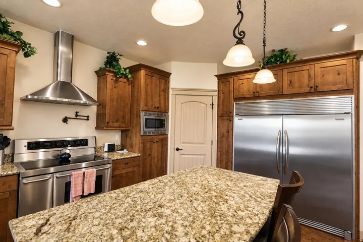Kitchen featuring wood cabinetry, stainless steel appliances, recessed lighting, and a stone-finish countertop