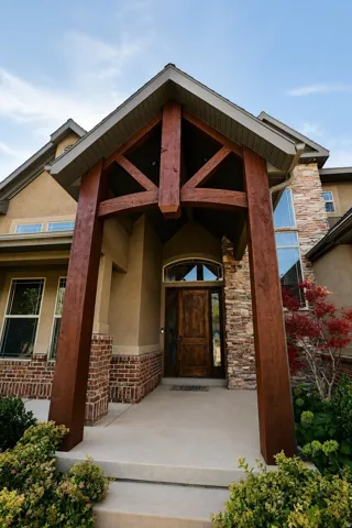 Crafted timber entry with an arched wood-panel door, stone and brick exterior accents, and a stucco finish