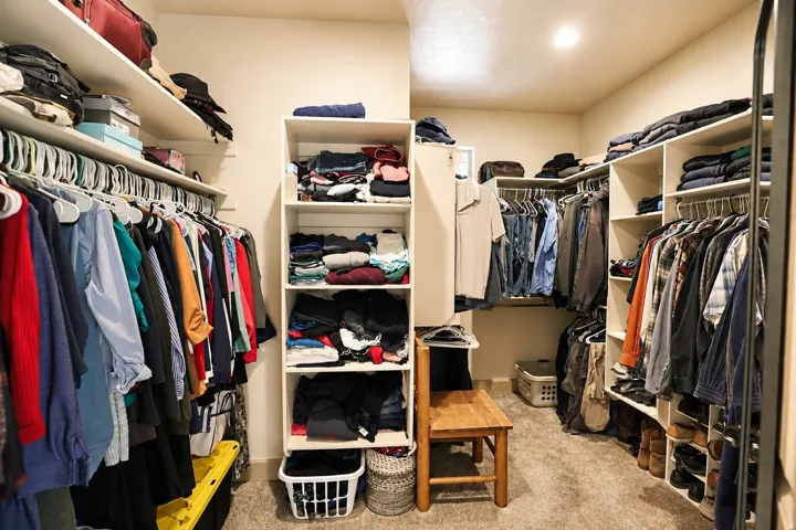 Built-in shelving, hanging rods, recessed lighting, and carpet flooring within a walk-in closet