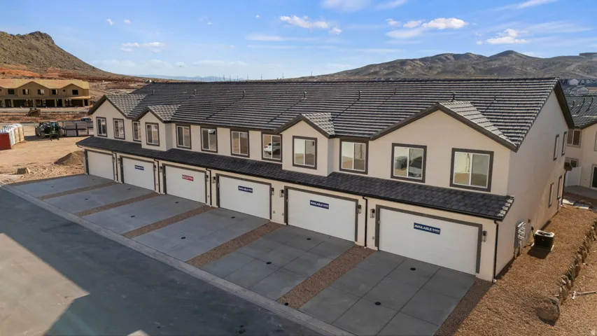 Multi-unit dwelling featuring stucco exterior, individual garage doors, and a tiled roof