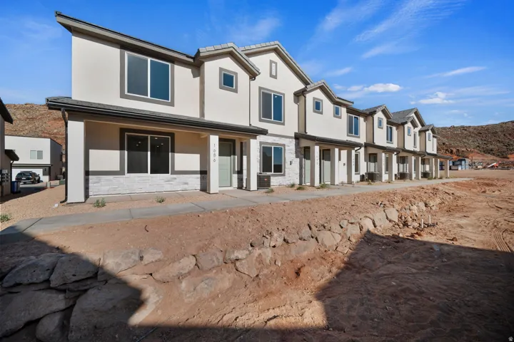 Modern townhouse exterior featuring stucco siding, stone accents, multiple large windows, and a covered entry