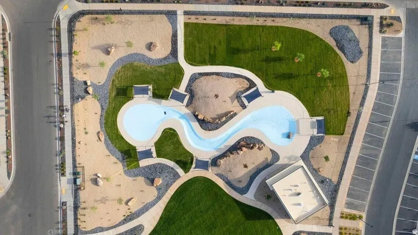 Community amenity featuring a winding water feature, surrounding green spaces, paved pathways, and an adjacent parking area