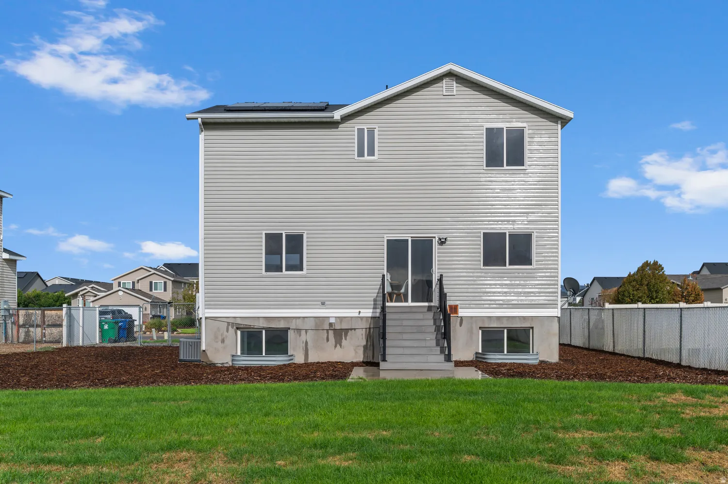 Two-story exterior with light gray siding, a prominent set of sliding glass doors, and a full-length staircase leading to the yard