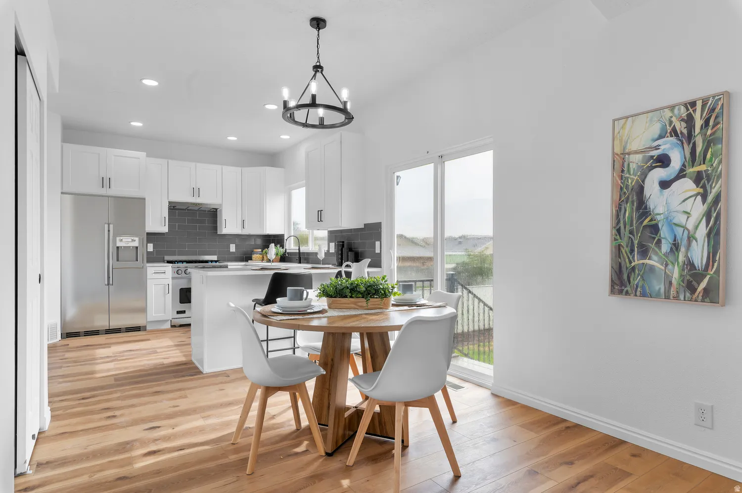 Kitchen featuring white cabinetry, stainless steel appliances, dark subway tile backsplash, and wood-finish flooring