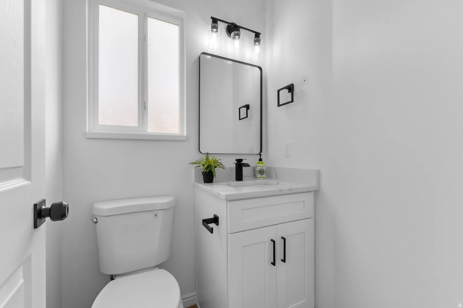 White vanity with a light-colored countertop, undermount sink, and matte black faucet