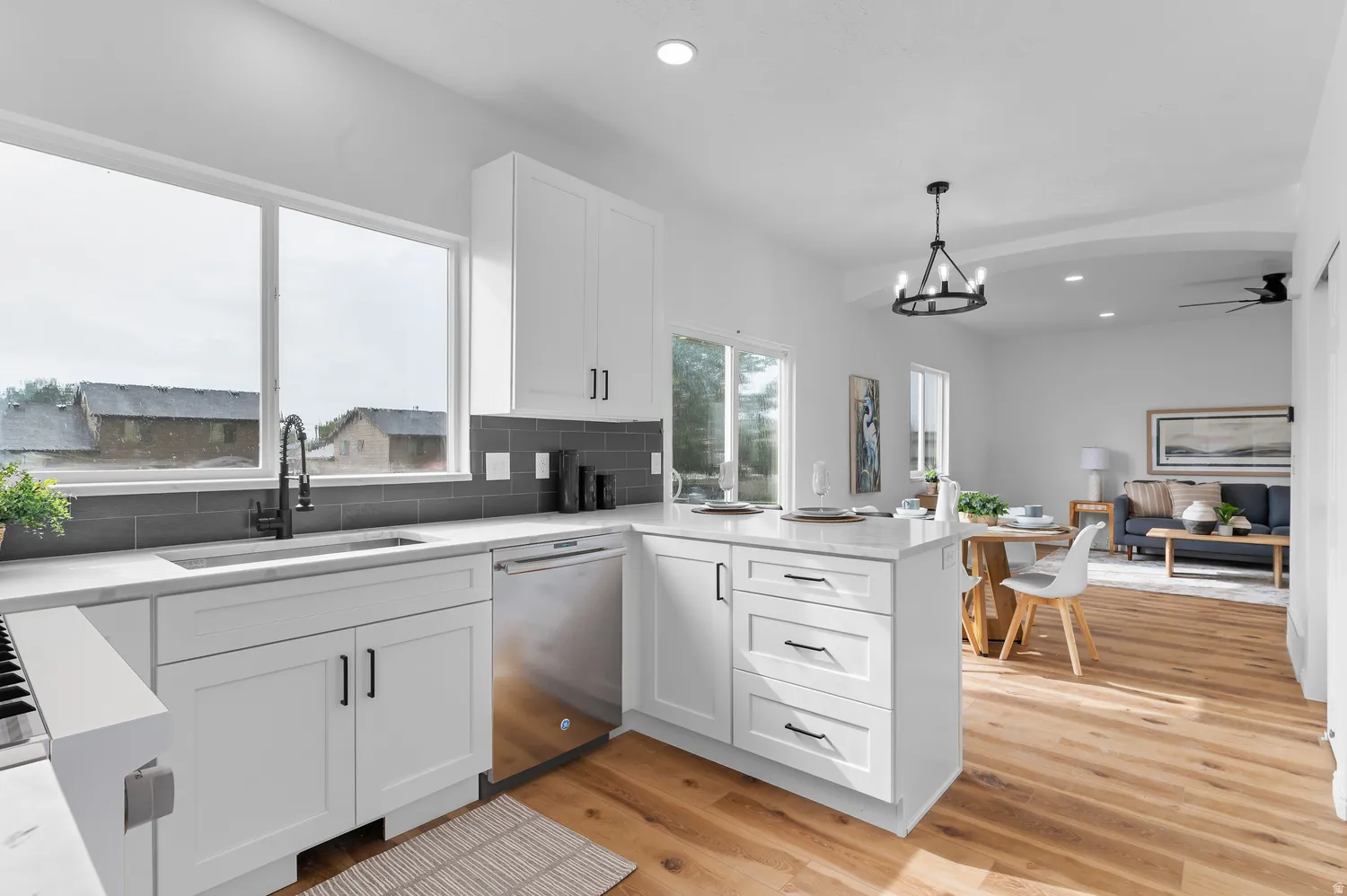 White cabinetry with black hardware, wood-finish flooring, recessed lighting, and a kitchen island with seating