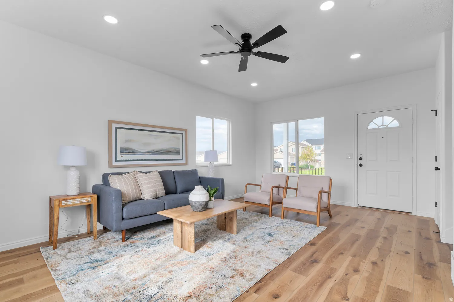 Recessed lighting, wood-finish flooring, white entry door with arched window, multiple windows, and a ceiling fan