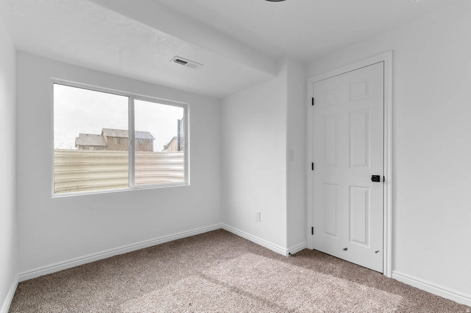Neutral wall color, carpet flooring, egress window, white trim, and a paneled door with dark hardware