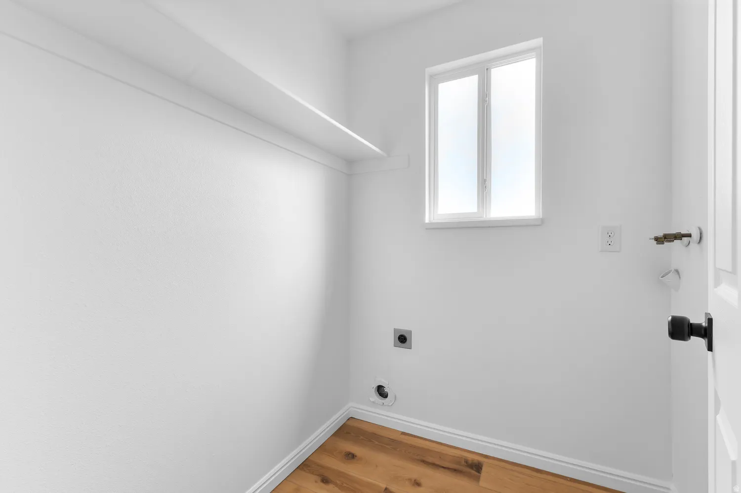 Single fixed shelf, white walls, wood-finish flooring, and a single window