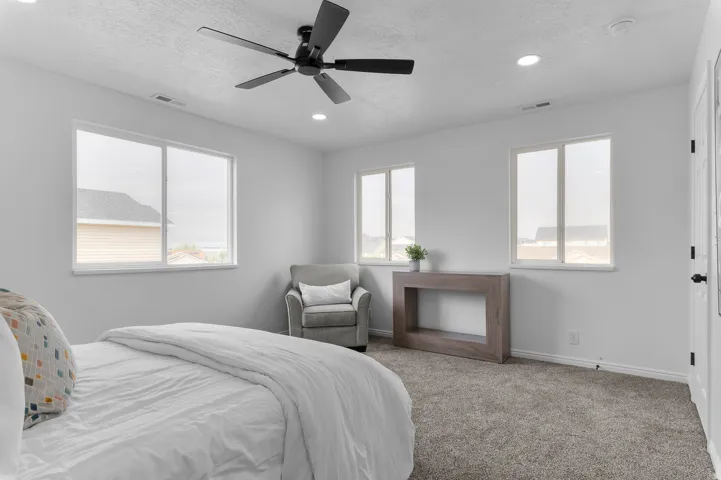 Recessed lighting, ceiling fan, three windows, and carpeted flooring
