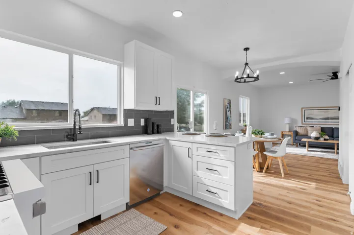 White cabinetry with black hardware, wood-finish flooring, recessed lighting, and a kitchen island with seating