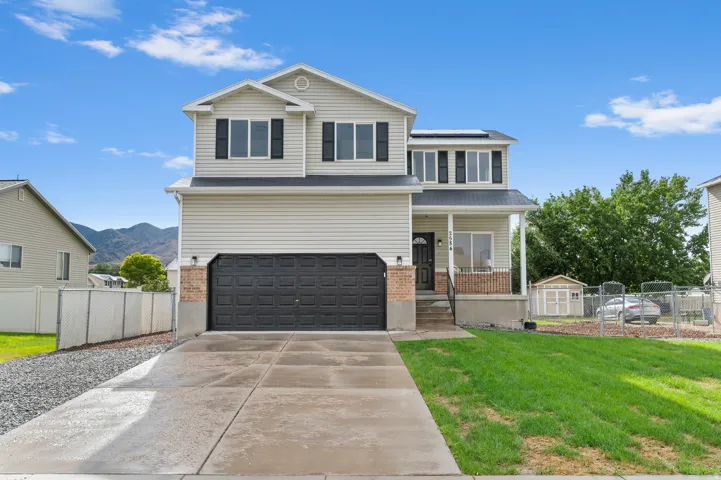 Two-story residence featuring light-colored siding, a covered front porch, and an attached two-car garage