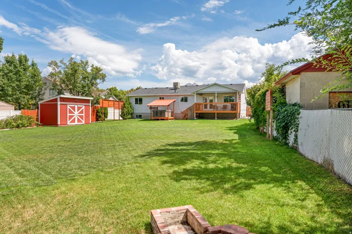 Expansive lawn with a red storage shed, wood deck, and a wood-frame shelter