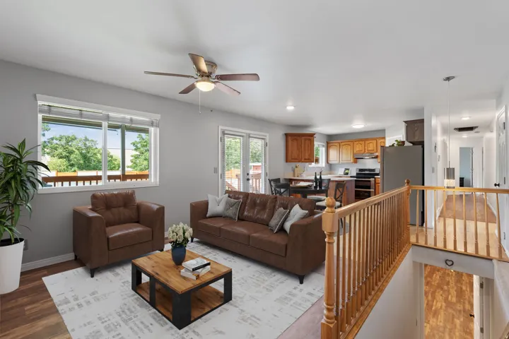 Open-concept living area featuring wood-finish flooring, a ceiling fan, and a large window