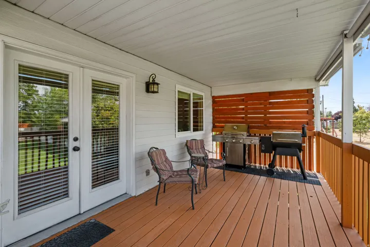Covered outdoor patio featuring French doors, wood-finish decking, and a slatted privacy wall
