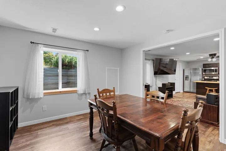 Recessed lighting throughout, wood-finish flooring, and a wide cased opening to the kitchen