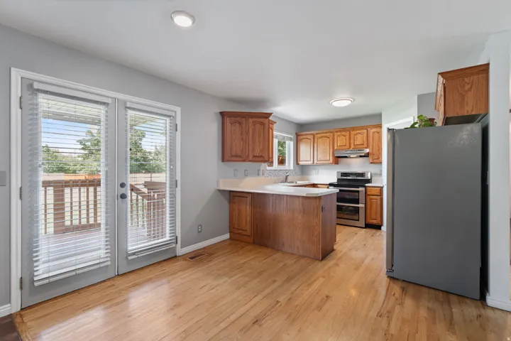 Hardwood flooring, wood cabinetry, stainless steel appliances, light-colored countertops, and outdoor access via French doors