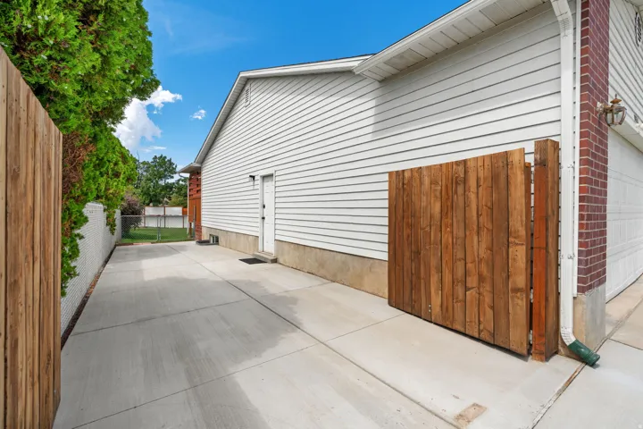 Concrete driveway with a wood-panel fence and white siding