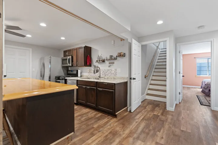 Kitchen featuring wood-finish flooring, recessed lighting, wood cabinetry, stone countertops, and a tiled backsplash