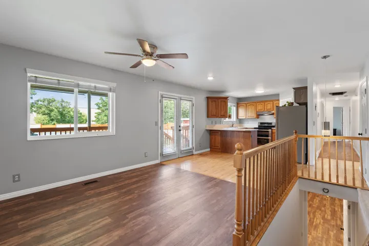 Open-concept living space featuring wood-finish flooring, a ceiling fan, and access to a deck