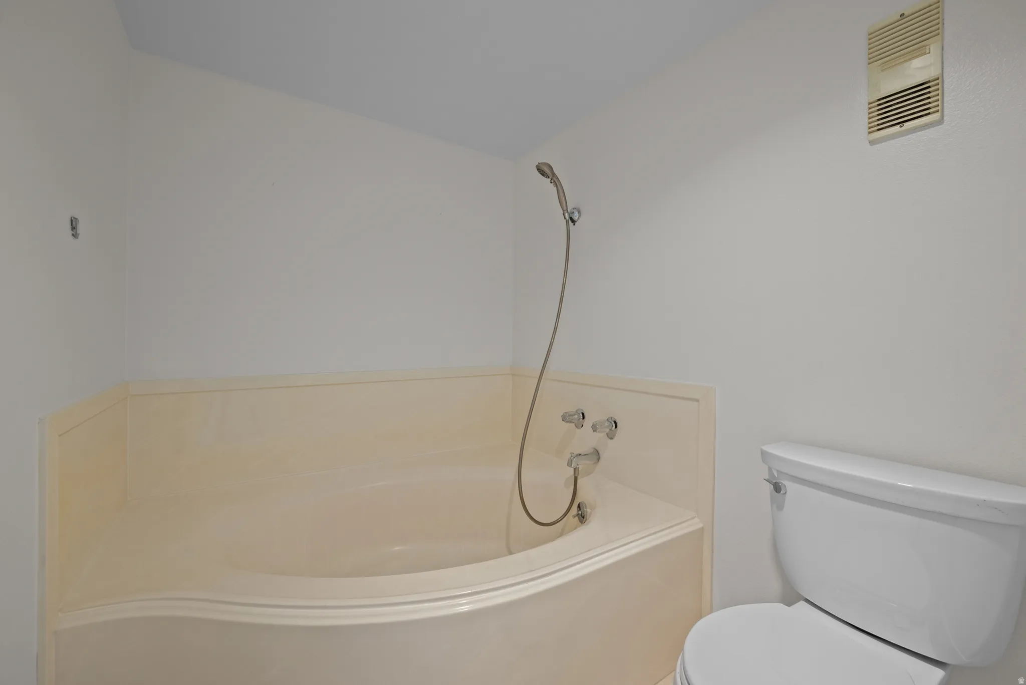 Corner soaking tub with a handheld shower fixture
