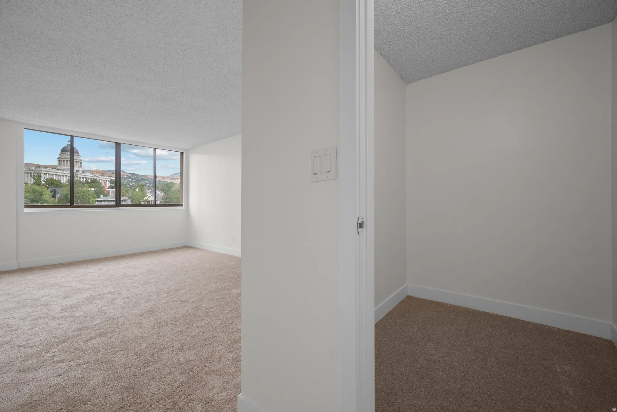 Spacious room with large windows, wall-to-wall carpeting, and a neutral color palette