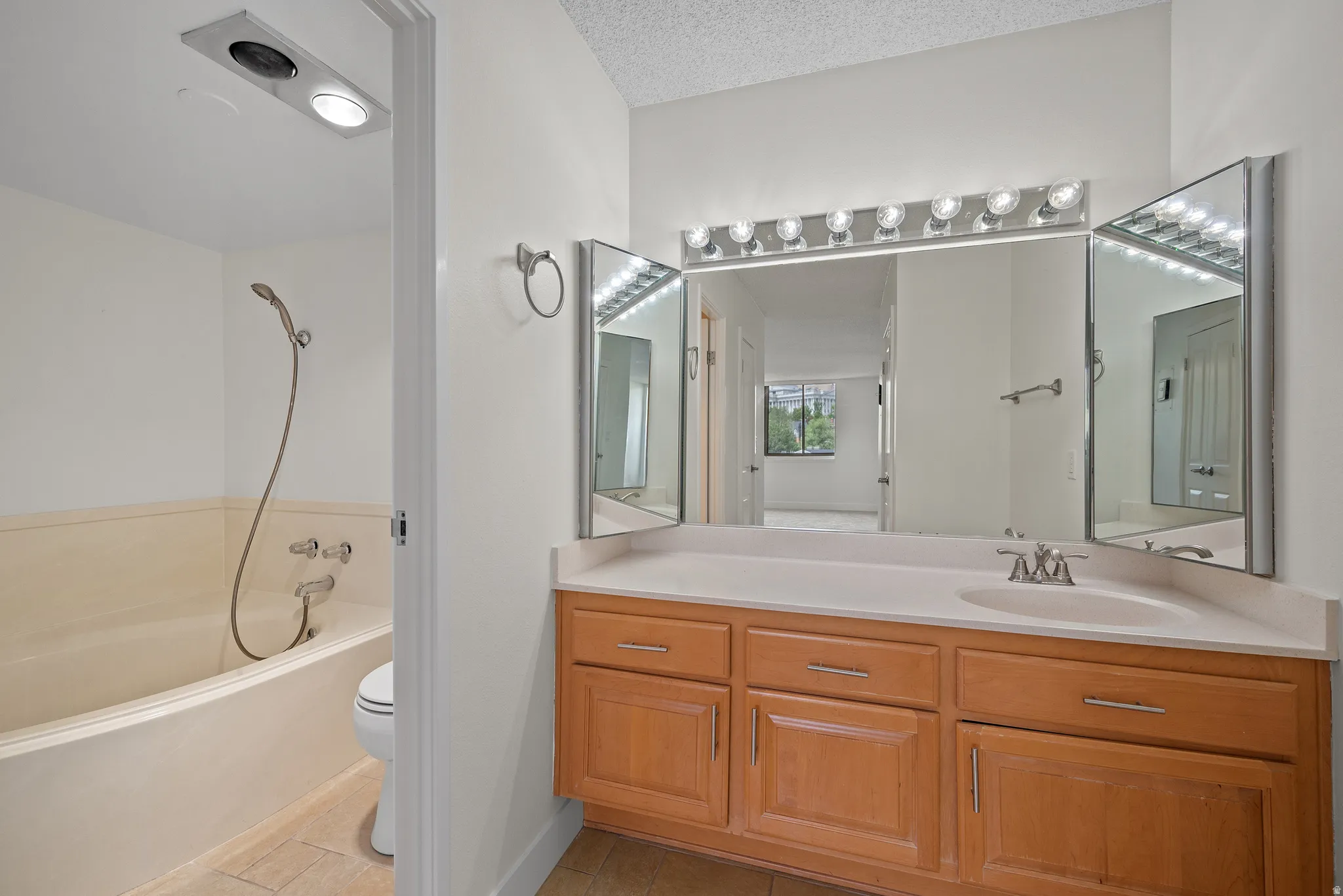 Bathroom featuring a built-in bathtub with shower, toilet, and vanity with an integrated sink
