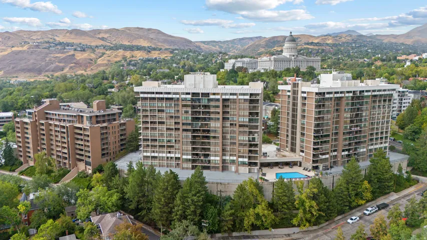 High-rise residential complex with multiple buildings, a prominent outdoor swimming pool, and surrounding mature trees