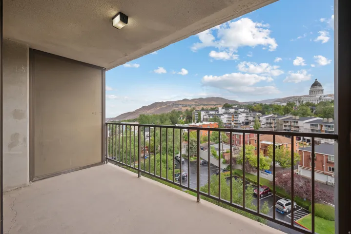 Balcony with metal railing, concrete flooring, and an exterior light fixture