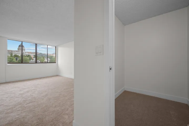 Spacious room with large windows, wall-to-wall carpeting, and a neutral color palette
